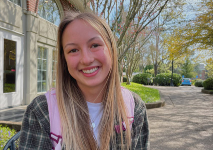 Lucy Kerr '24 sitting down outside of Starbucks, smiling