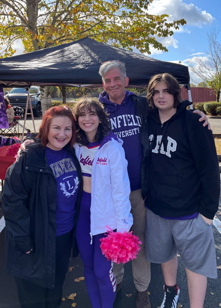 Matigan in their dance uniform with their parents and brother before the Fall Family Weekend football game