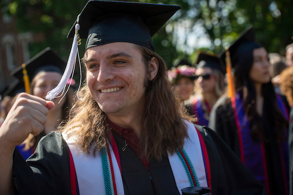 Excited student in cap and gown at 2023 Commencement.