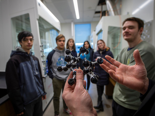 A professor demonstrating a new tool for six students.