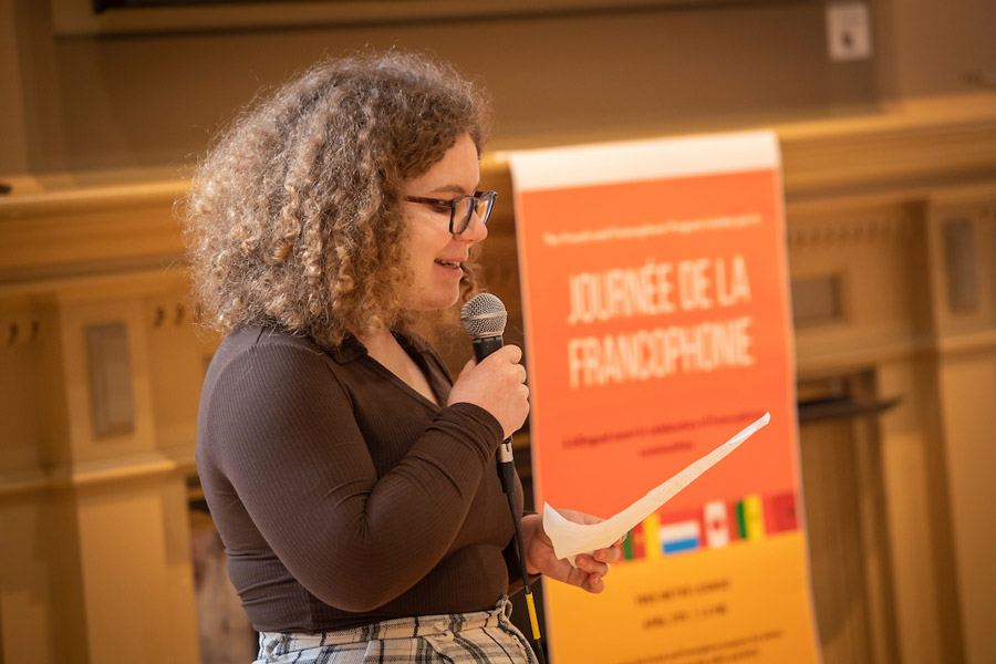 Female student holding microphone giving oral presentation.