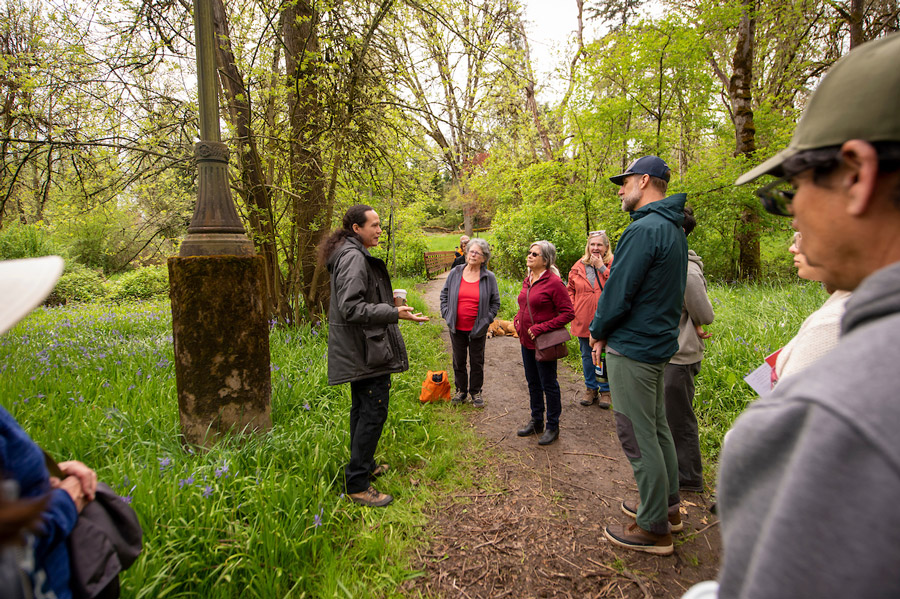 A member of the Confederated Tribes of Grand Ronde speaks about camas to a group of people touring Cozine Creek.