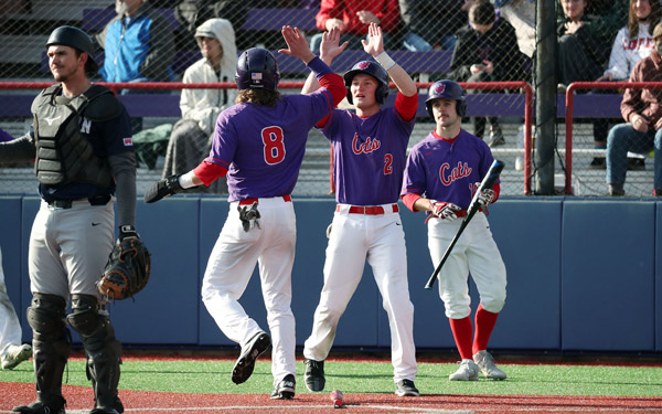 Three Linfield basebal players celebrating after a run