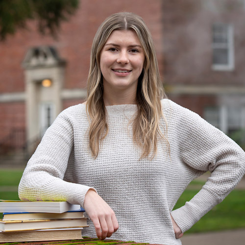 Portrait of a female student with a stack of books.